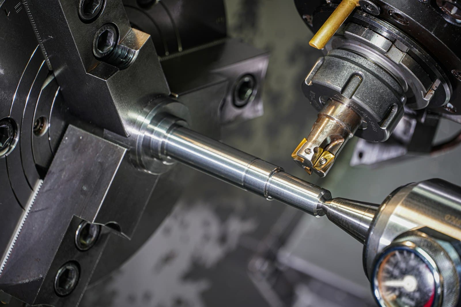 A metal shaft held in a lathe chuck being cut by a live tool