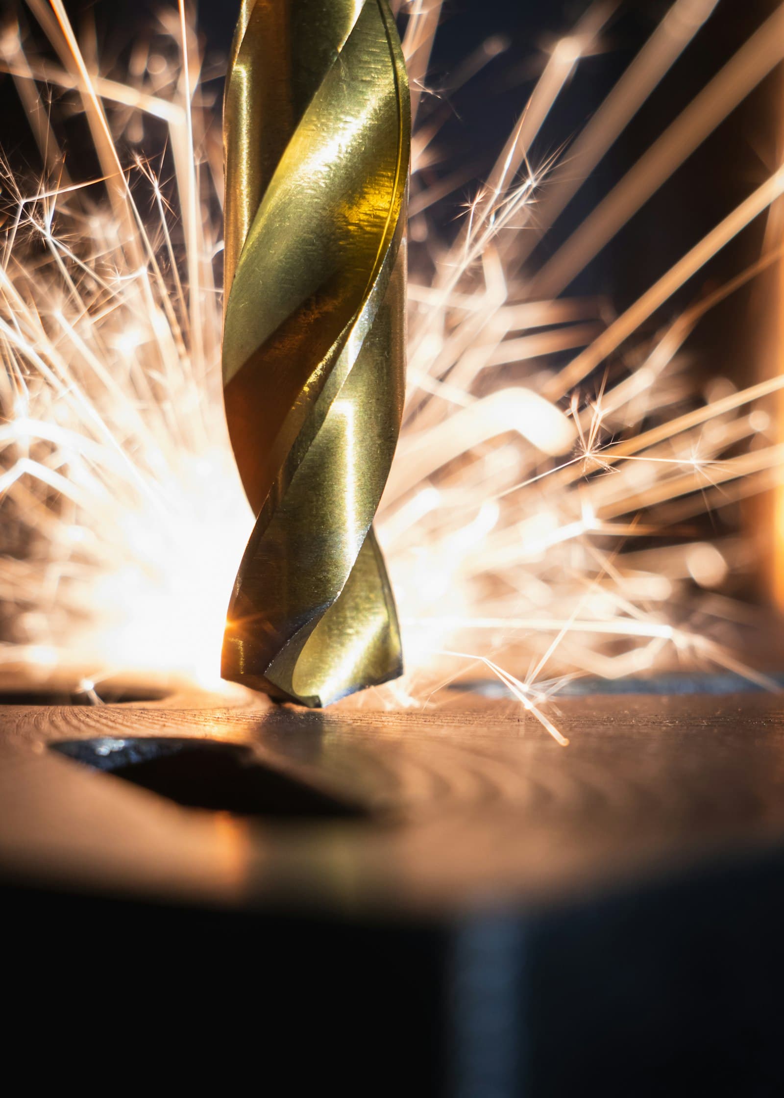 A cutting tool machining a dark metal surface, throwing sparks